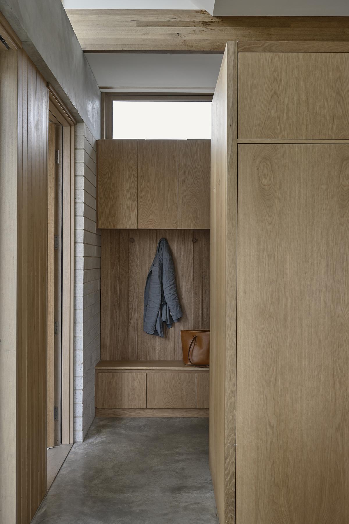 built in wooden storage in an entryway with concrete floors