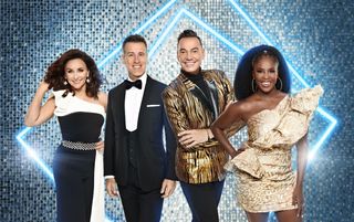 A group shot of Strictly judges Shirley Ballas, Anton Du Beke, Craig Revel Horwood and Motsi Mabuse in front of a silver glitter backdrop with light blue neon lights