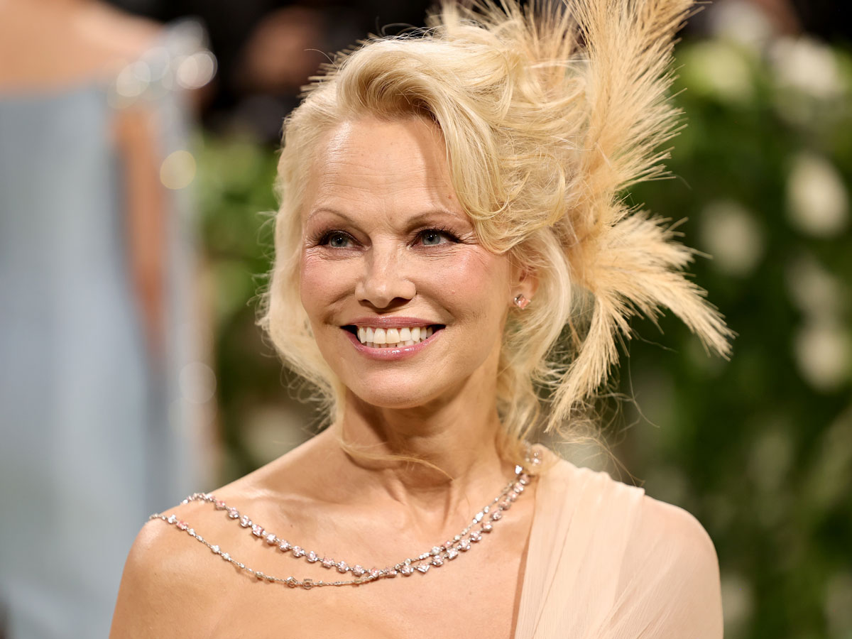 Pamela Anderson smiles wearing a crystal necklace at the 2024 Met Gala