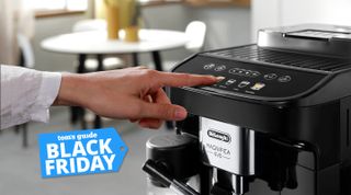 A finger pressing a button on the De'Longhi Magnifica Evo with a Tom's Guide Black Friday deals label