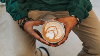 Man holding a cup of coffee with latte art