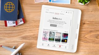 A white digital e-reader displaying kobo plus on a wooden table with a passport and model plane