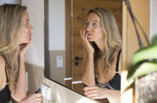 A woman applying foundation while looking in a mirror