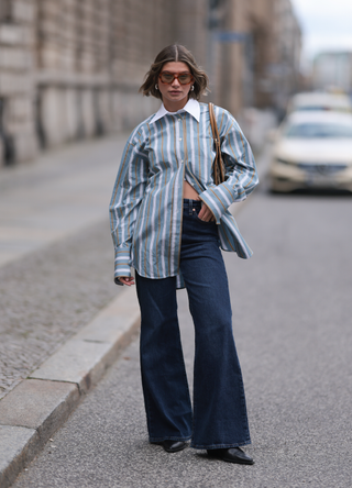 Sophia Geiss seen wearing a beige brown Gucci vintage bag, LeGer black cowboy boots, Levi’s flared denim dark blue wide trousers, H&M Studios blue and white striped shirt, Vehla brown eyewear shades on April 02, 2024 in Berlin, Germany