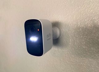 eufyCam 2C installed on a wall with floodlight illuminated