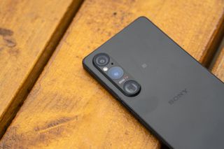 A black Sony Xperia 1 V camera phone sitting on a wooden table