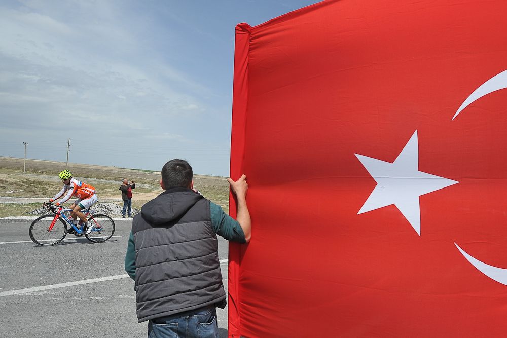 A spectator with a Turkish flag as the peloton passes