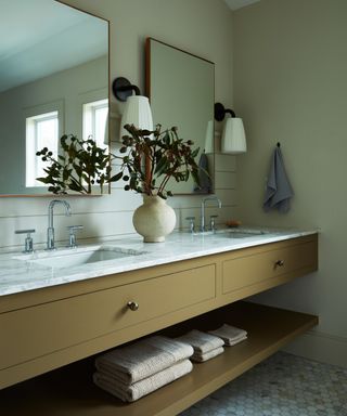 bathroom with khaki brown washstand, marble countertop and twin mirrors