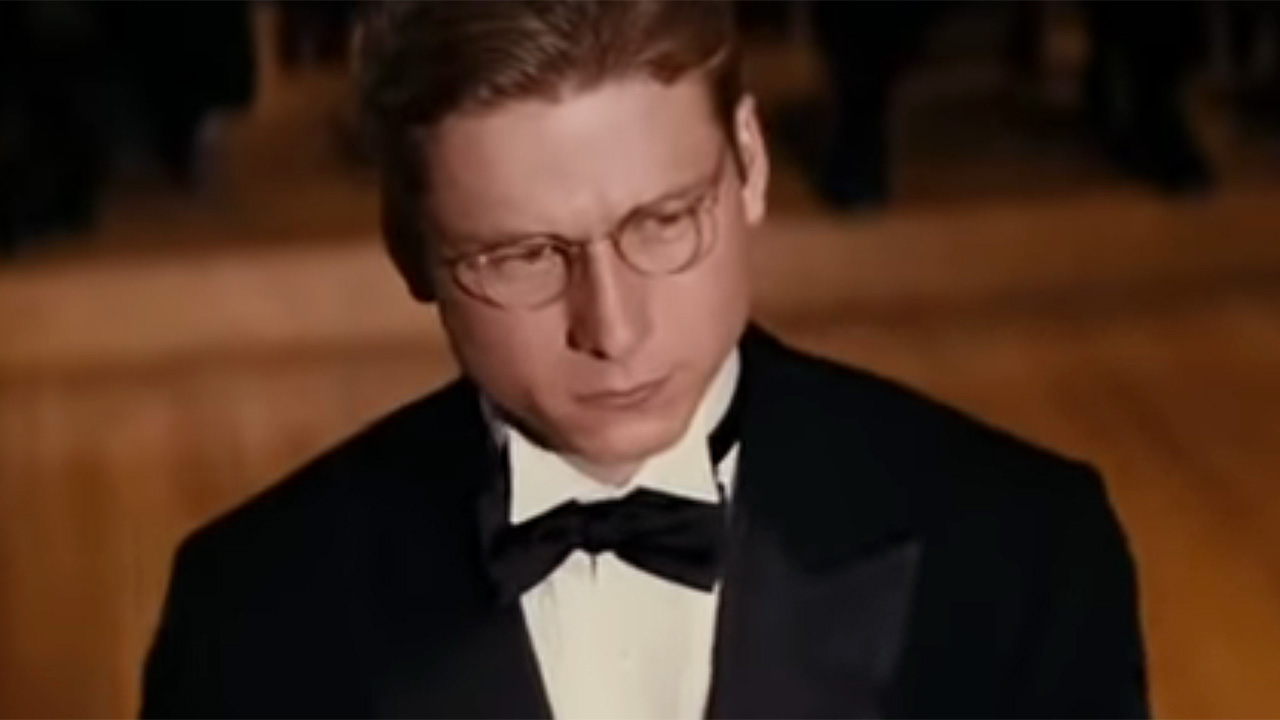 Glen Powell wear a tux and bowtie, as well as glasses, while onstage debating in The Great Debaters.