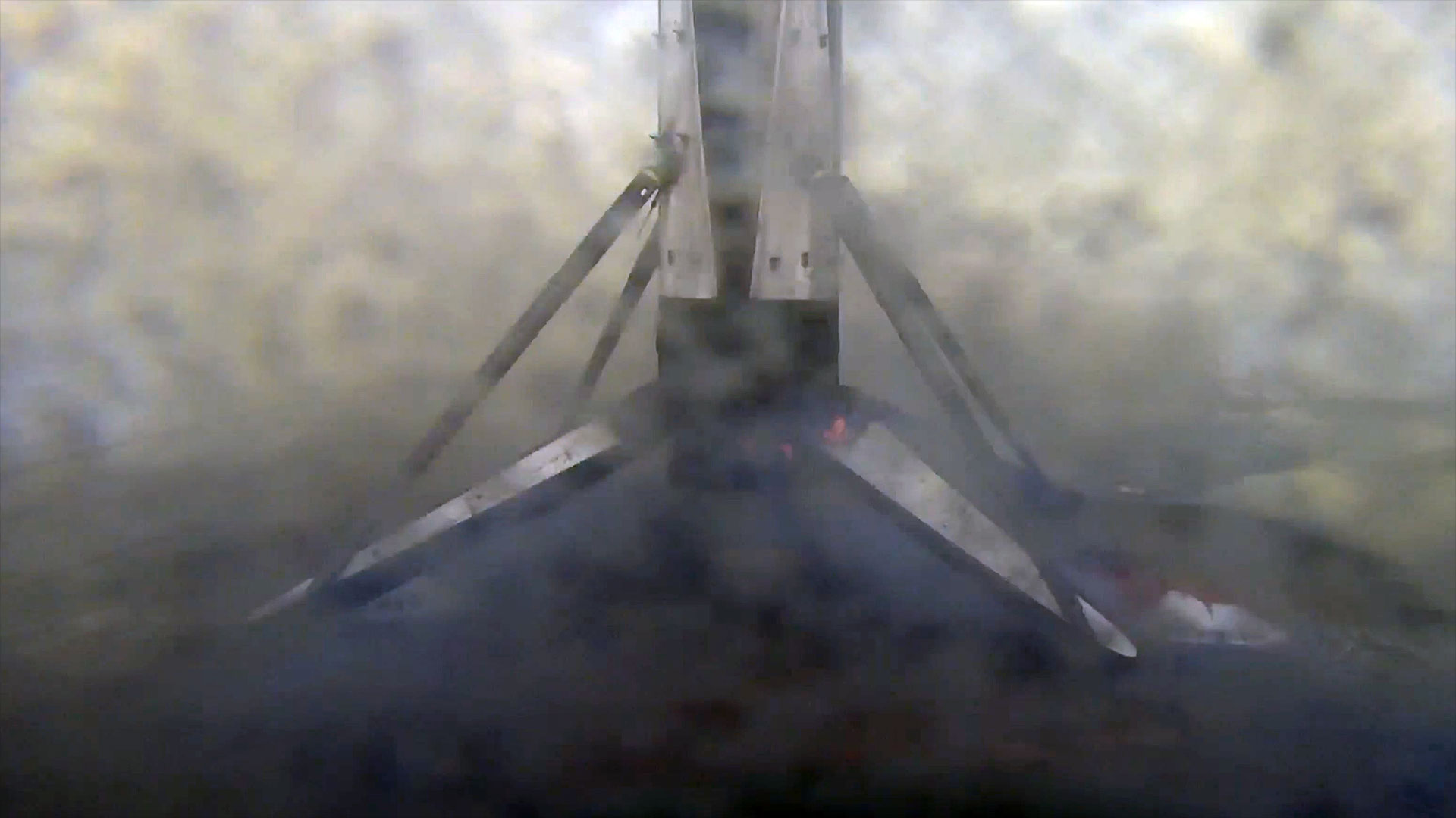 the first stage of an orbital rocket stands on four legs atop an ocean-based platform after landing from space