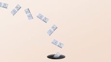 Stacks of dollar bills falling into a dark hole in the ground.