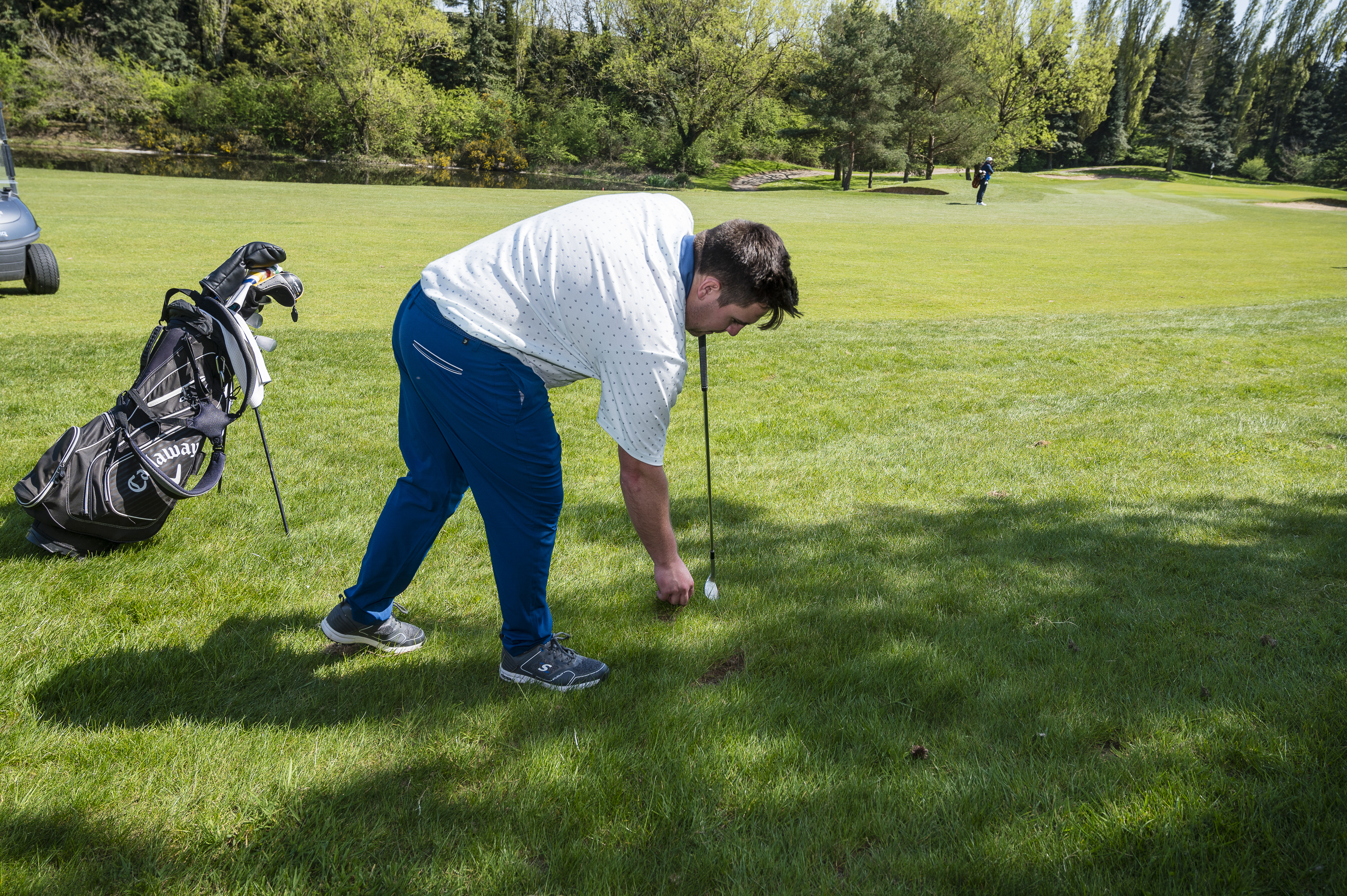 A golfer repairs a divot on the course