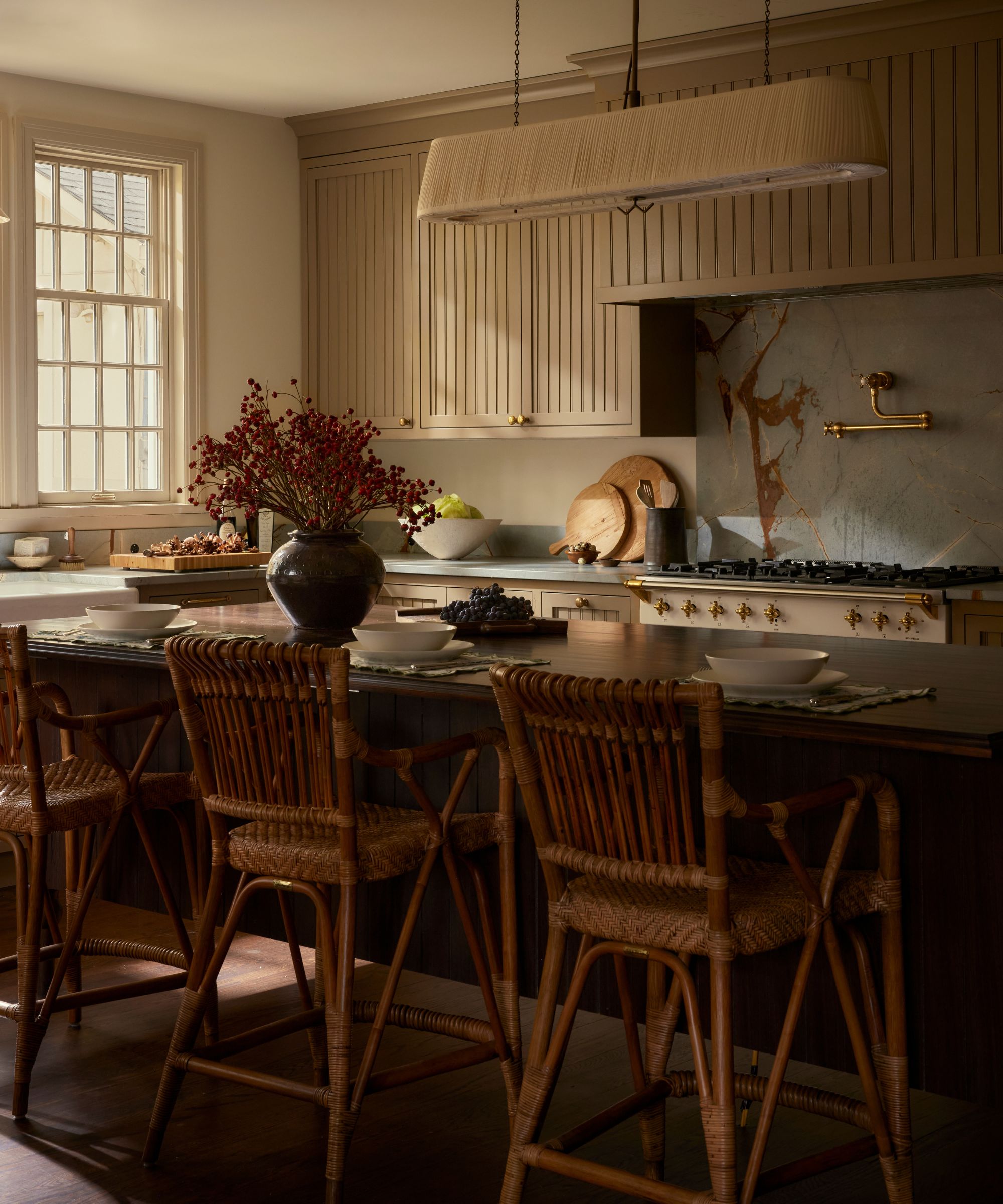 A warm neutral kitchen with slatted cabinets and a large dark wood island featuring turned legs for a furniture-style design