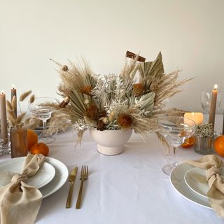 christmas flower arrangement using dried flowers on a white and brown natural theme kitchen table setting