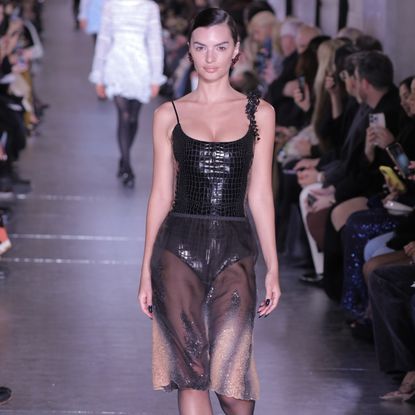 Emily Ratajkowski walking for Tory Burch in a croc-effect leotard and sheer knee-length skirt 