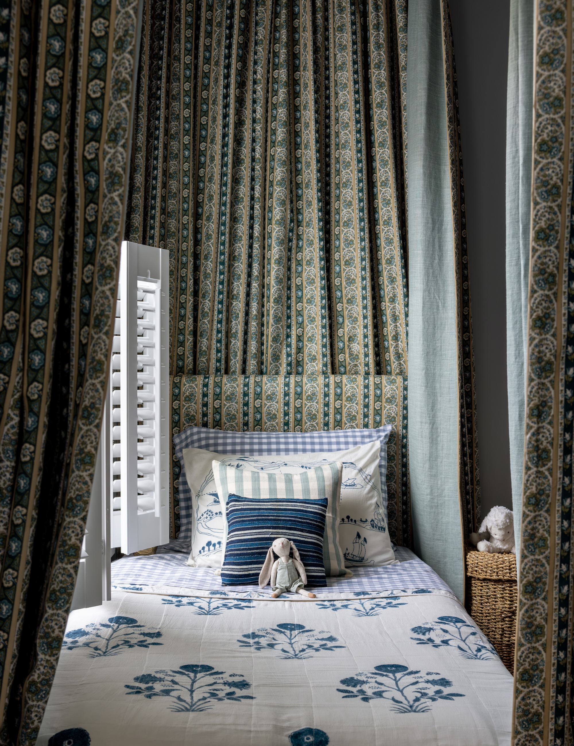 Layered children's room featuring a bed with a draped canopy covering and bed linens of various patterns