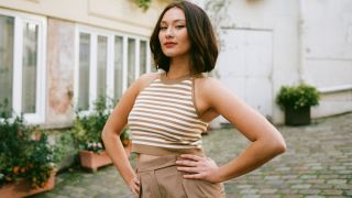 Lola Tung standing with her hands on her hips looking powerful.