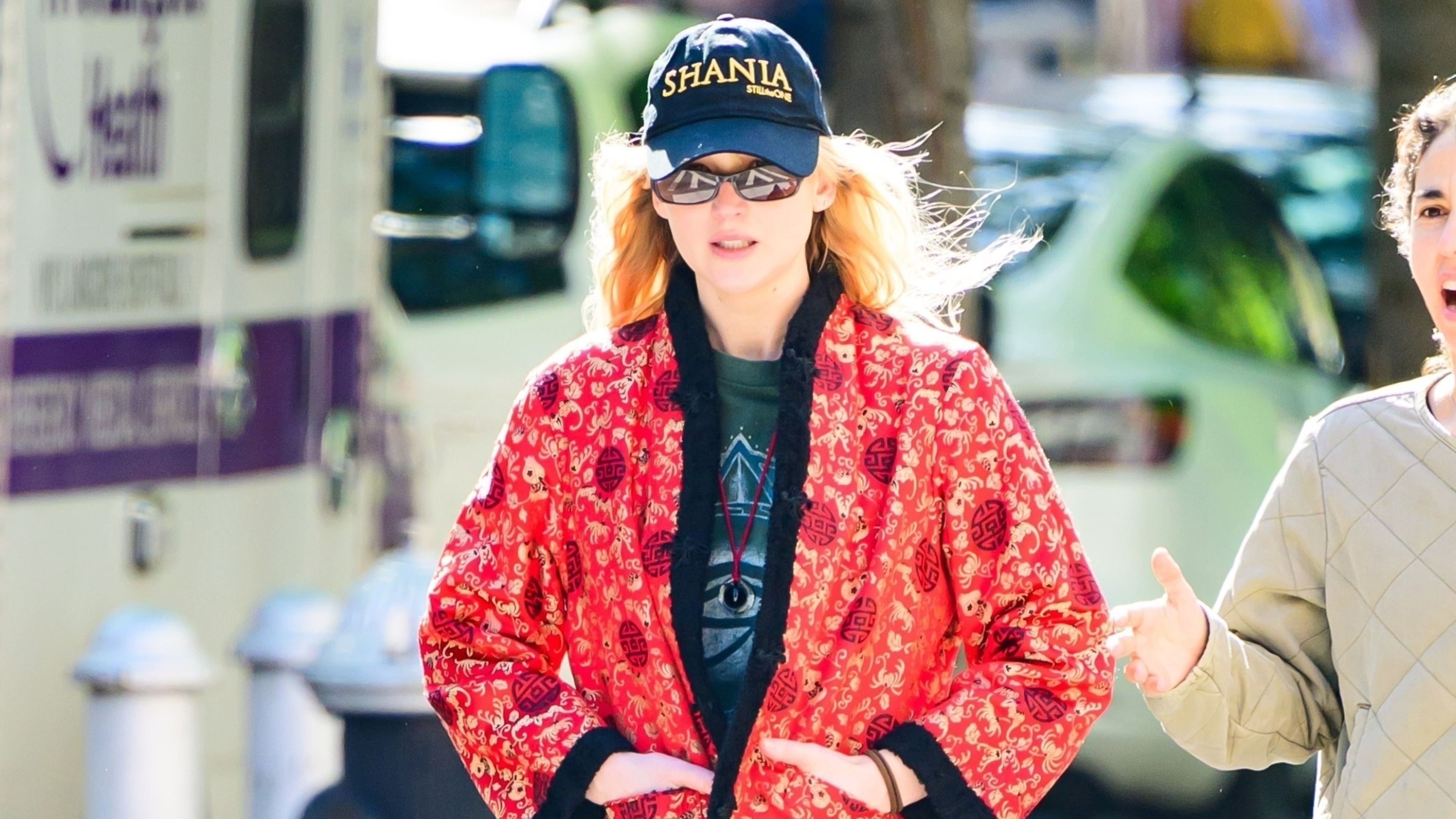 Jennifer Lawrence wears a Shania hat, red jacket, black pants, and black ballerina sneakers.