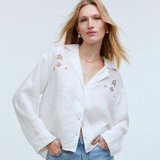 model wears white embroidered eyelet top with blue jeans
