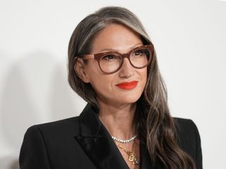 Jenna Lyons wears large eyeglasses and a black blazer