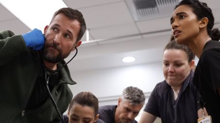 A team of doctors crowd around an operating table
