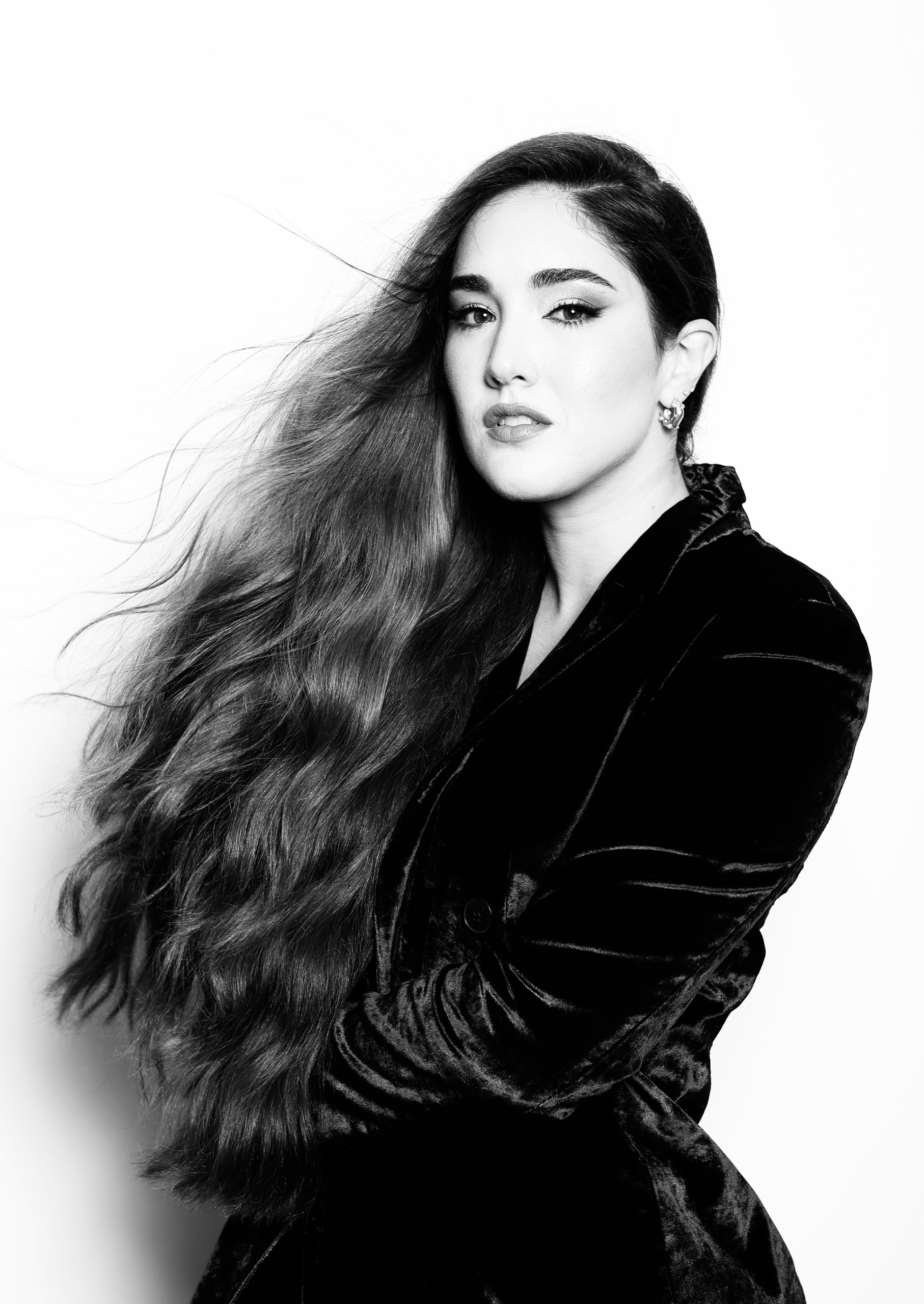 a black and white photo of a woman with long hair in a velvet blazer
