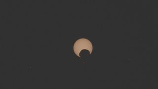 A blurry photo of Mars' moon Phobos passing in front of the sun in a partial eclipse