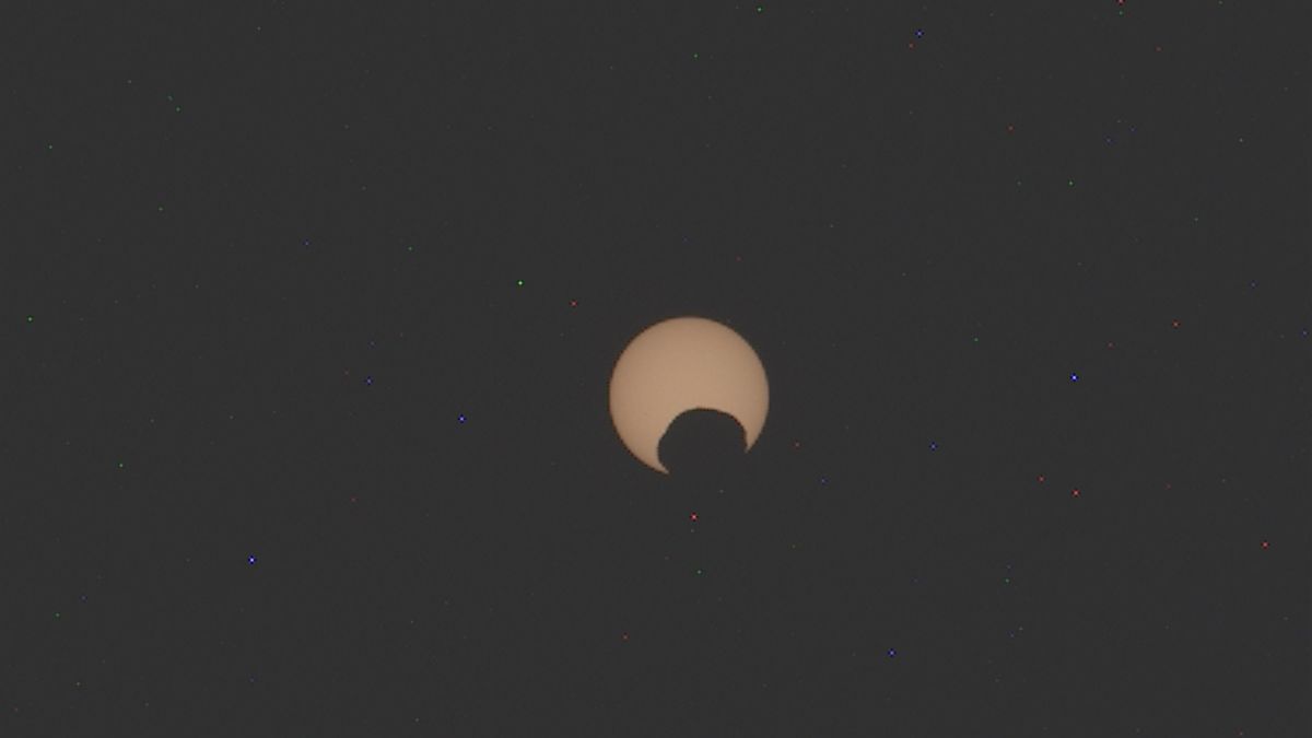 A blurry photo of Mars' moon Phobos passing in front of the sun in a partial eclipse