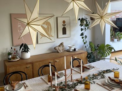 A dining room with the table laid with Christmas decorations and paper star lights hanging from the ceiling