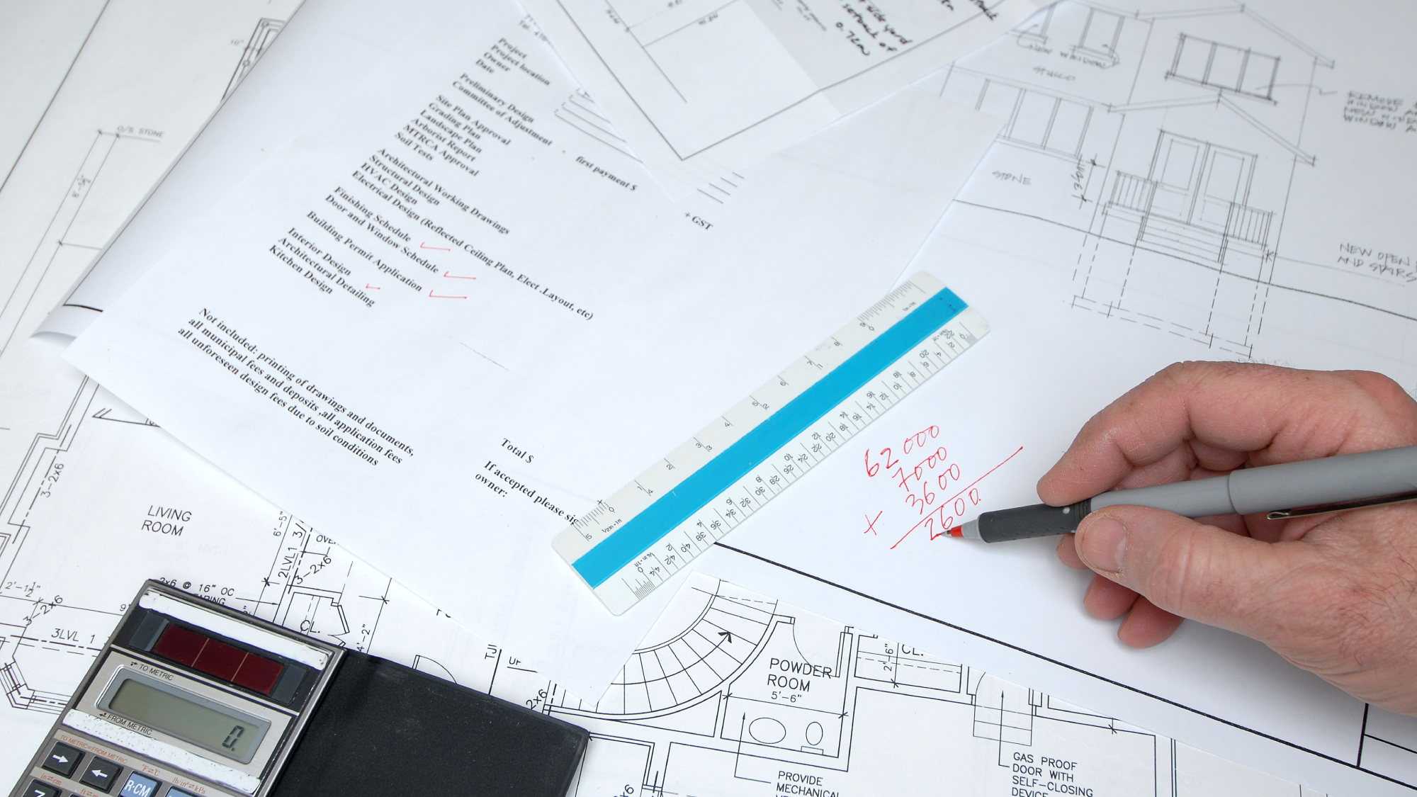 architectural drawings, paperwork, calculator, ruler and hand doing sum on paper