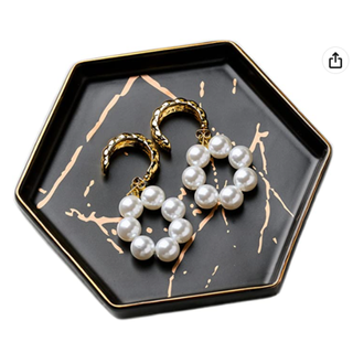 A geometric jewelry holder with pearl earrings in it