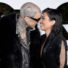 Kourtney Kardashian Barker and Travis Barker kiss on a red carpet