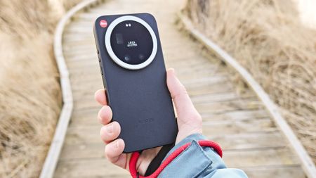 The Leica Leitzphone in person's hand with a wooden boardwalk backdrop
