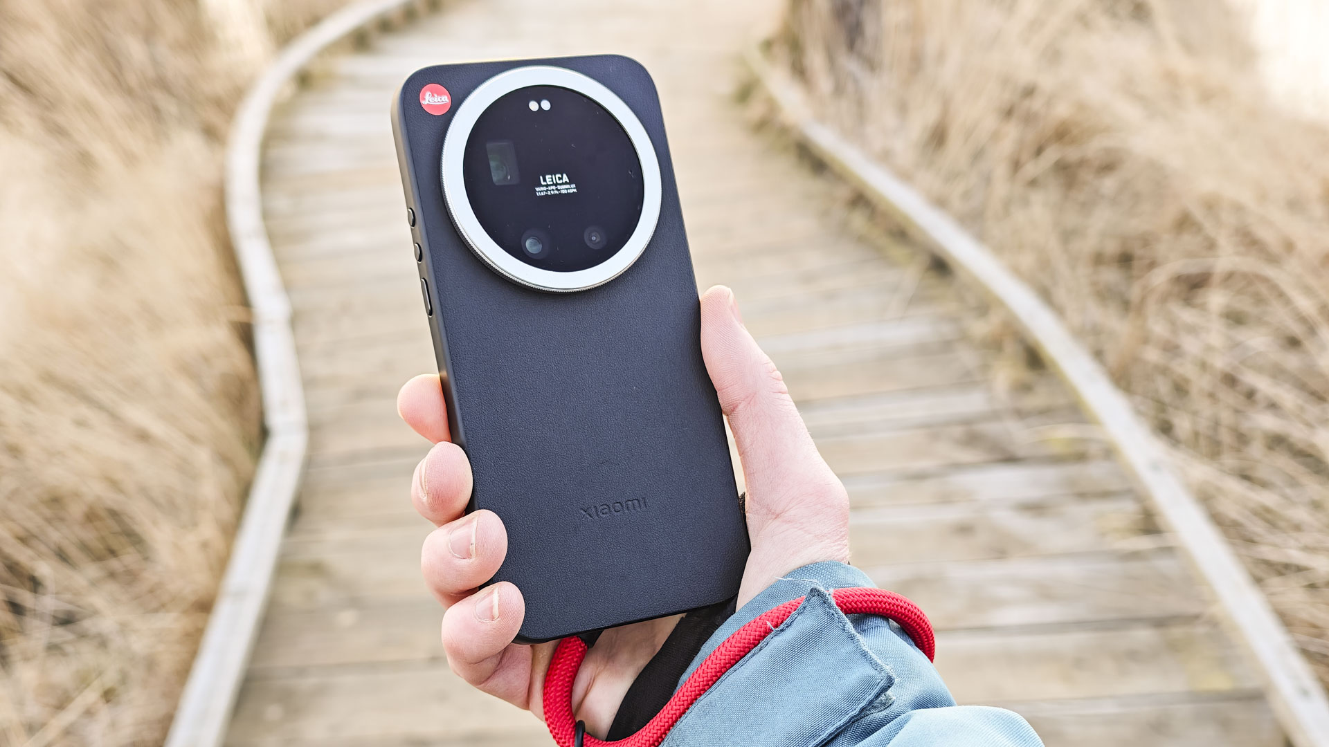 The Leica Leitzphone in person's hand with a wooden boardwalk backdrop