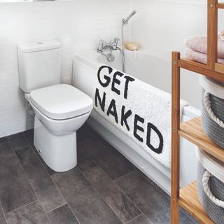 A bathroom with a slogan bath mat