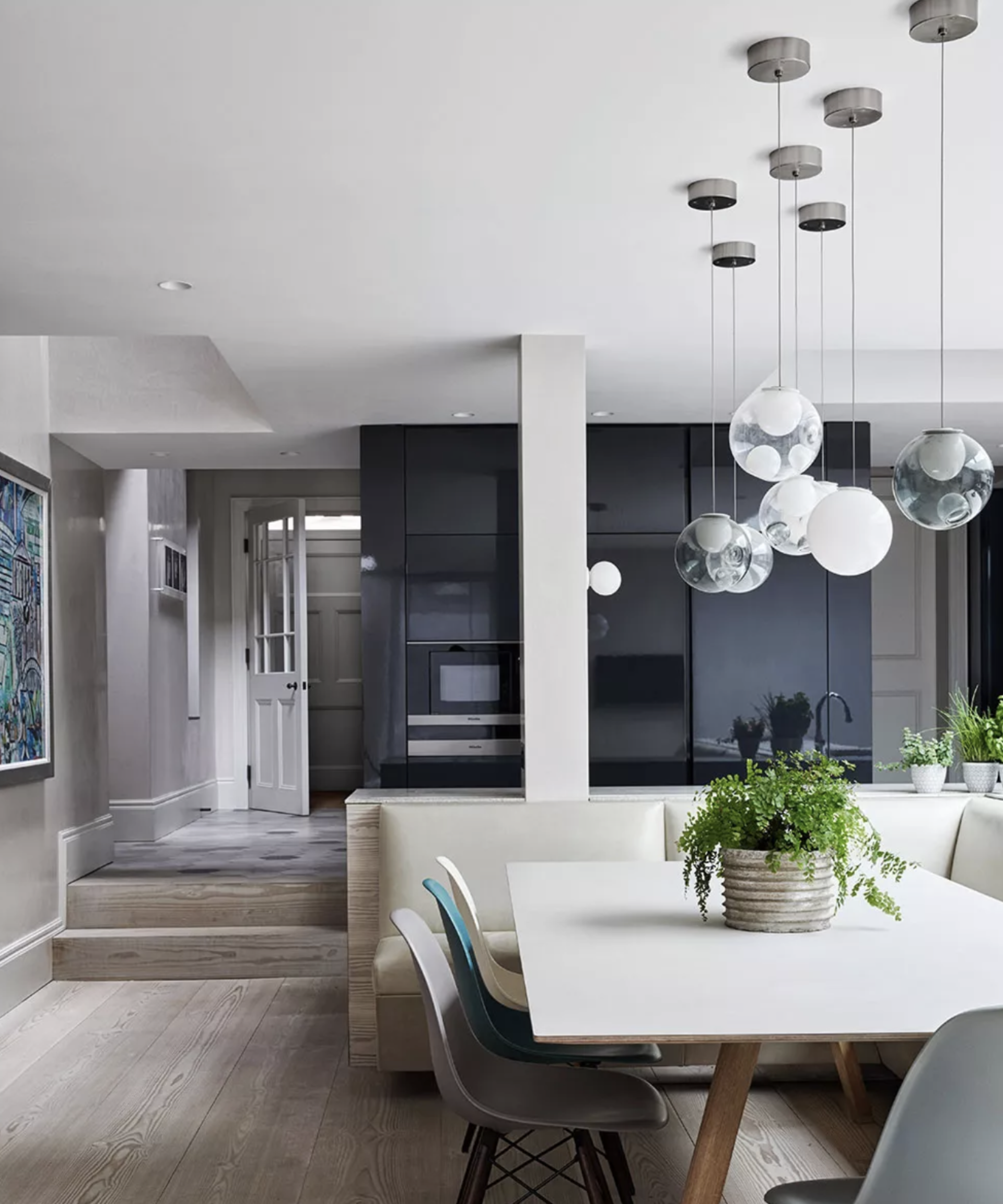 Circular glass pendants as an arty kitchen lighting idea over a white table.