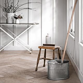 room with wooden floor and white wall and stool and brush and bucket