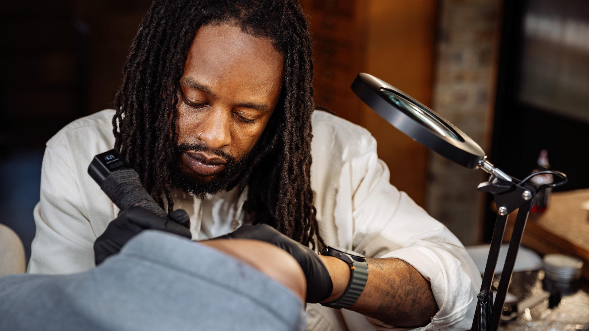A man giving a woman a tattoo on her arm.