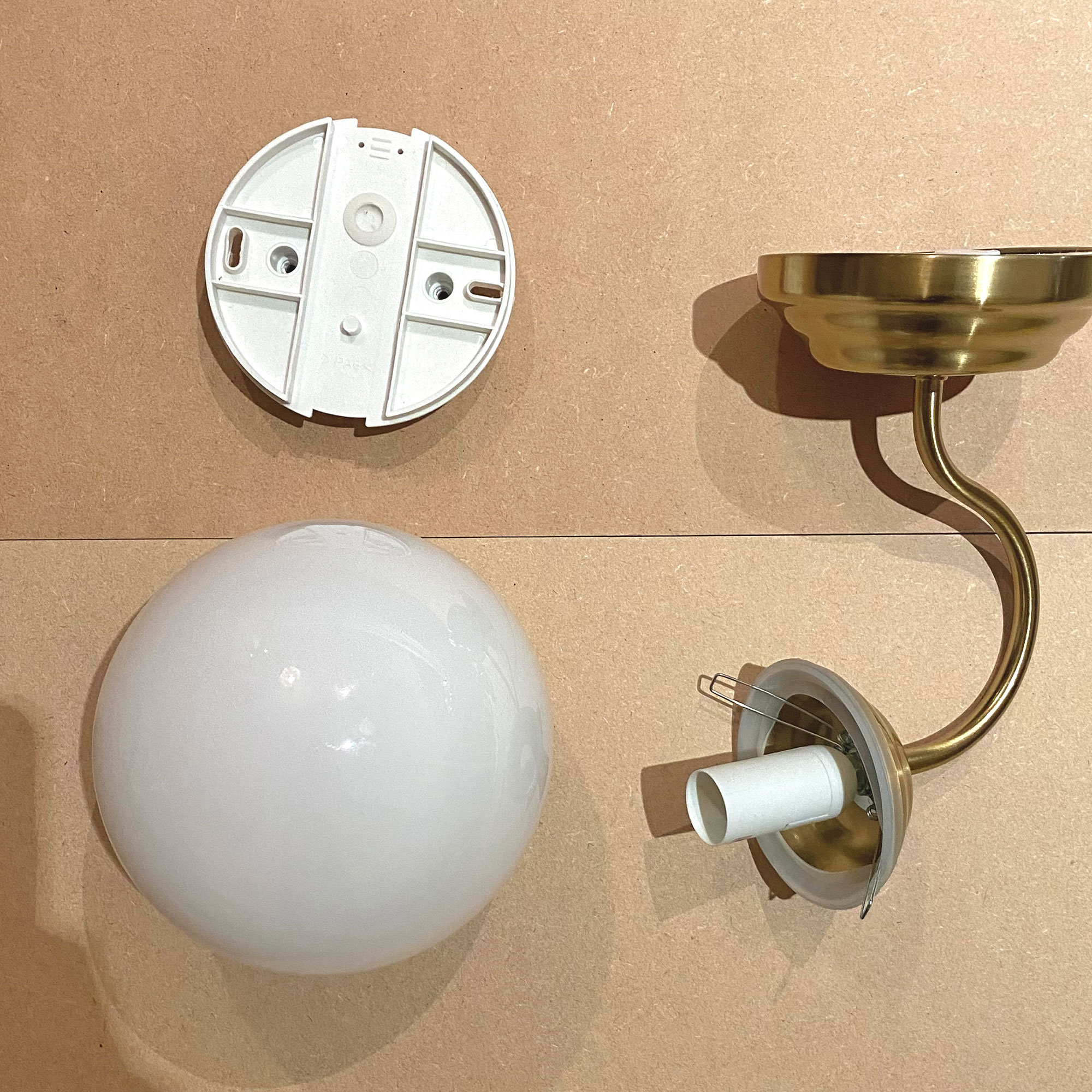 Pieces of wall light laid out on floor pre-assembly