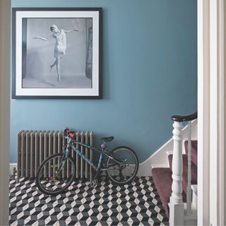 Blue hallway with patterned tiled floor and a bike resting against a radiator