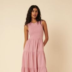 Woman wearing pink tiered dress with beige background.
