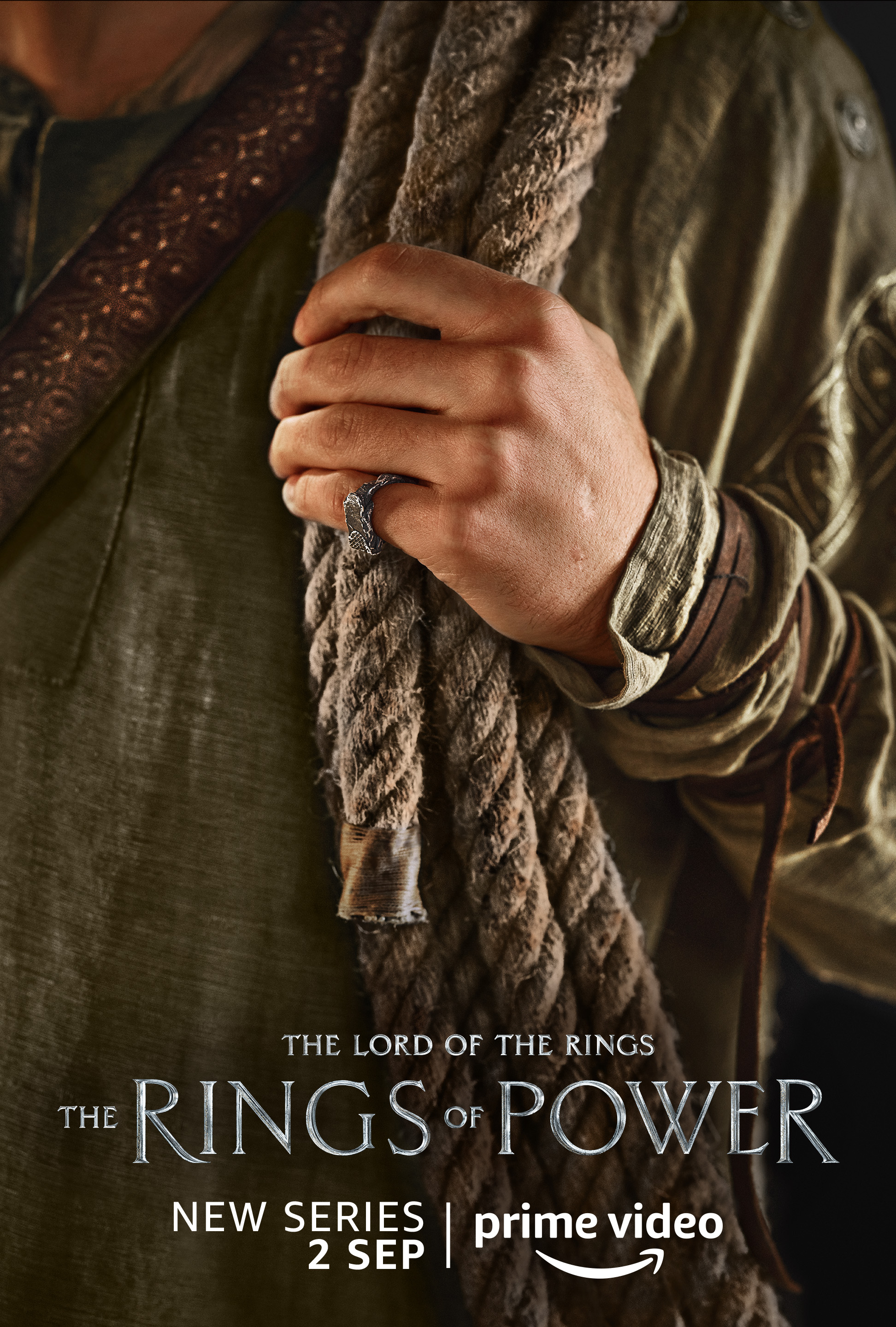 A human holding a rope character poster for Lord of the Rings: The Rings of Power