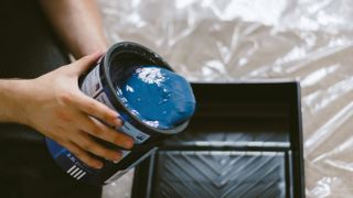 person pouring paint into container