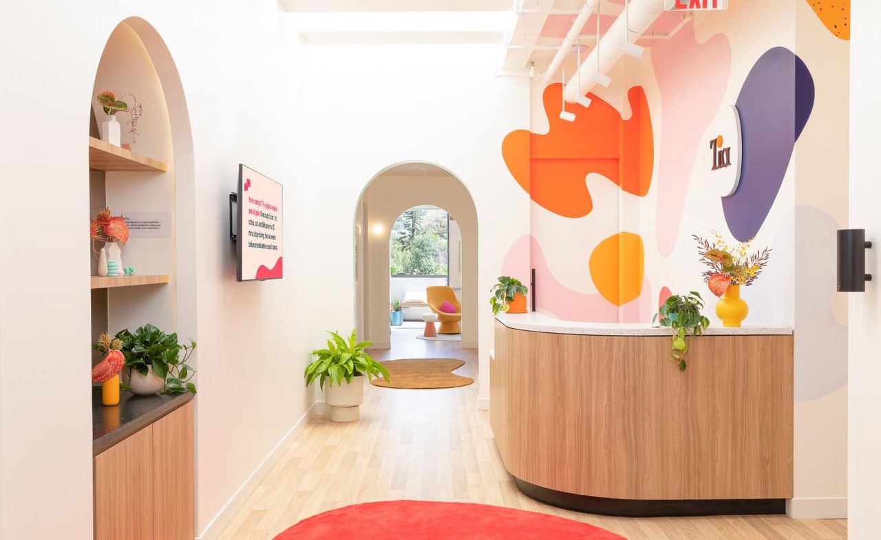 brightly designed reception area with orange rug and colourful puddles painted on the walls