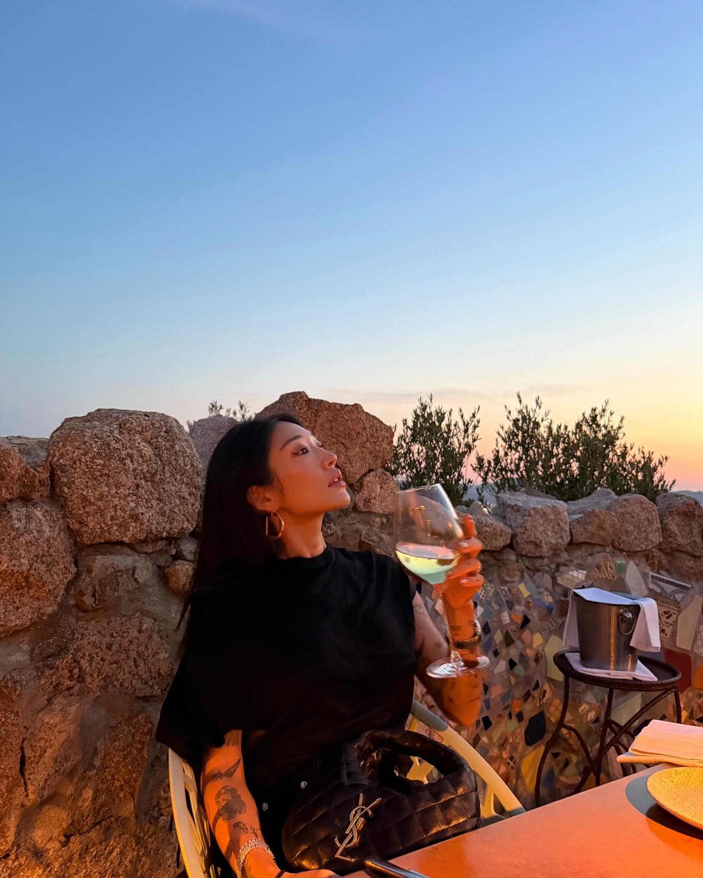 Peggy Gou wears black top sits at table with Saint Laurent iCarino