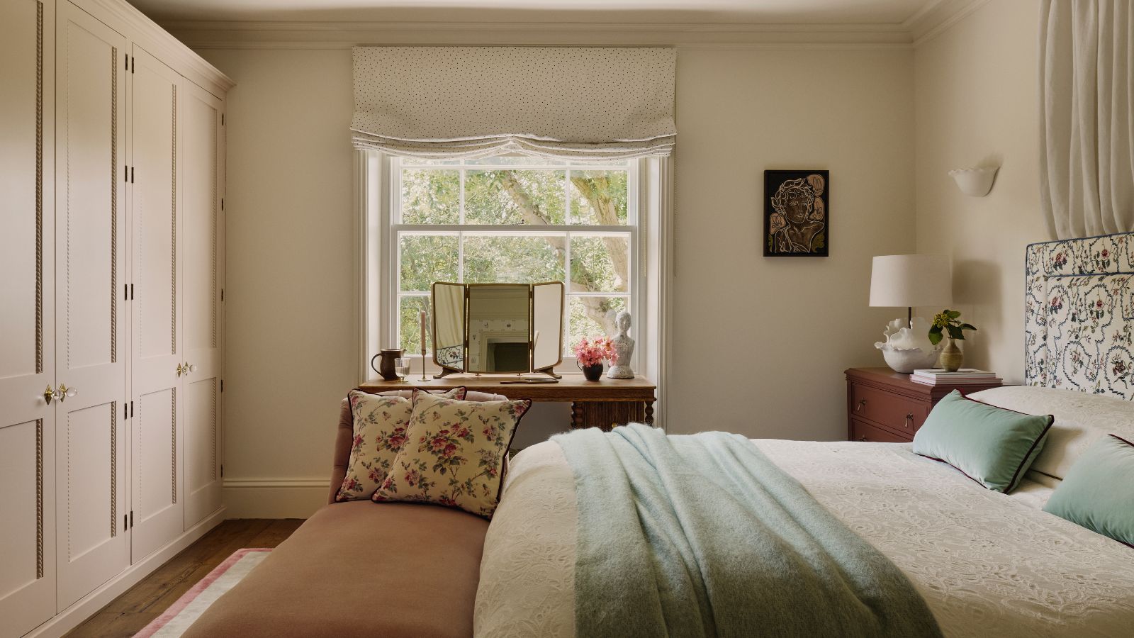 Traditional bedroom with cream walls, built in cabinets and a pattern headboard