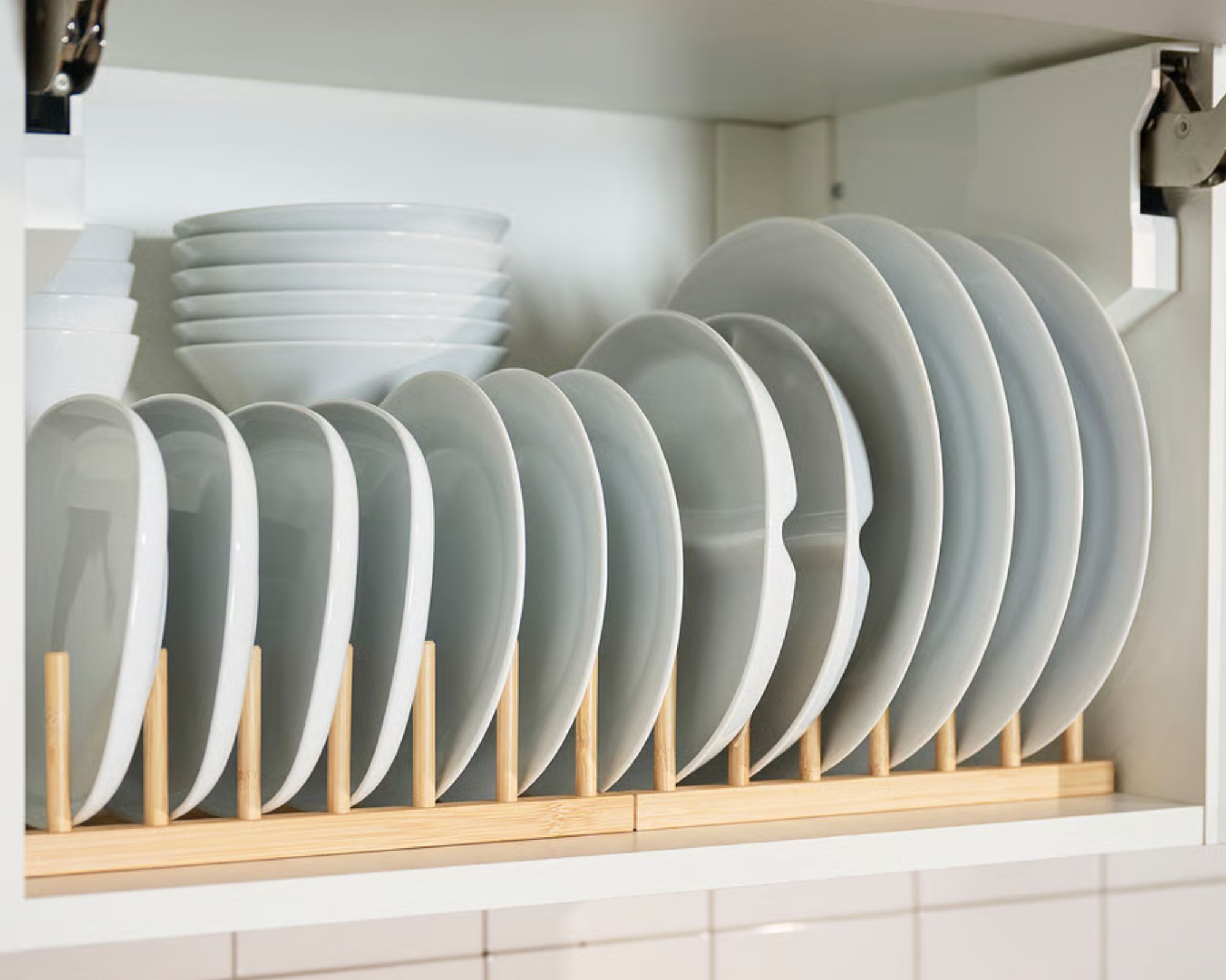 IKEA OSTBIT bamboo kitchen cabinet organiser in use. It shows two side by side, and holding 6 side plates, and six dinner plates in a cabinet with upward opening door