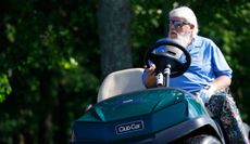 John Daly sits in a golf cart whilst watching on