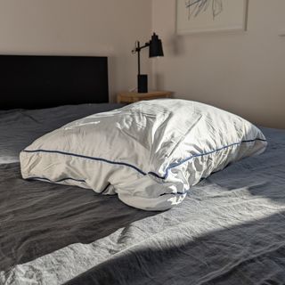 The Emma Original Hybrid Pillow being tested on a bed with a grey linen duvet cover