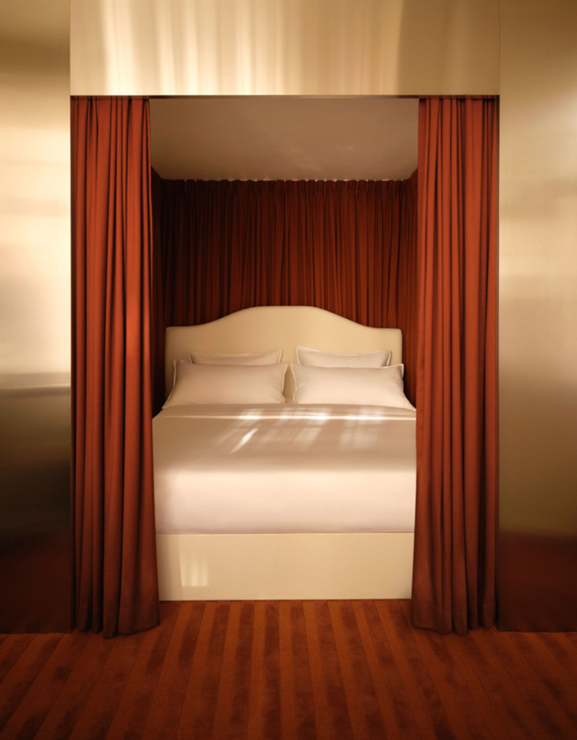 A white bed in a bedroom that has a chrome frame around the bed with red curtains and a matching red carpet